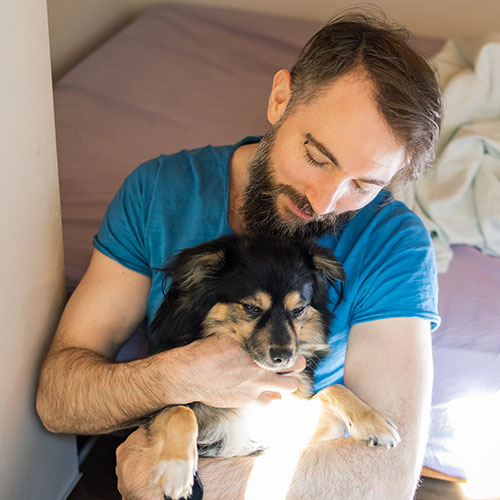 A dog showing love and affection while being held in a man's arms.